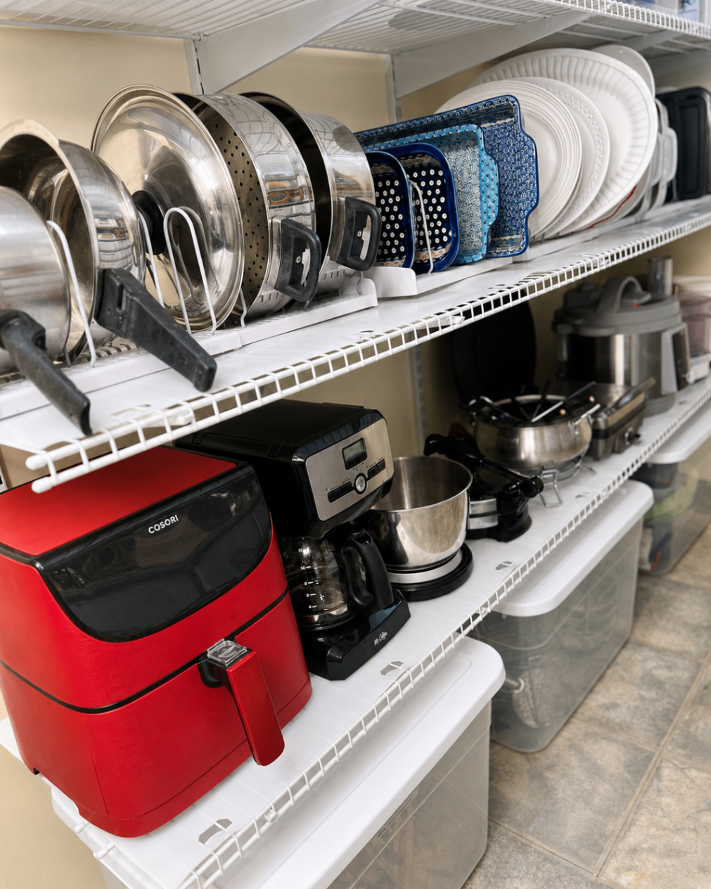 Kitchen storage area with pots, serving dishes, and small appliances neatly arranged.